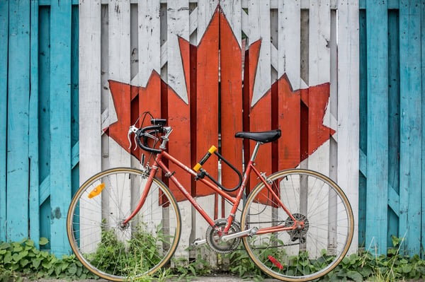 A bike leaning against a wall with the Canadian flag.