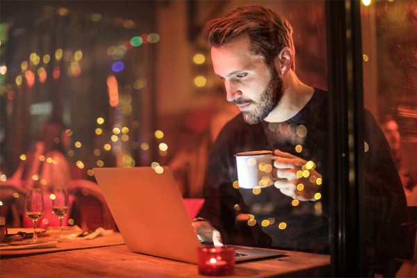 A person using a laptop in a cafe at night.
