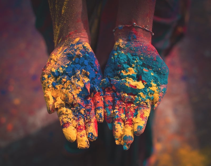 A person's hands covered in coloured chalk.