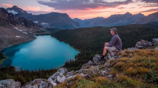 A person sitting at a scenic mountain viewpoint in Canada.