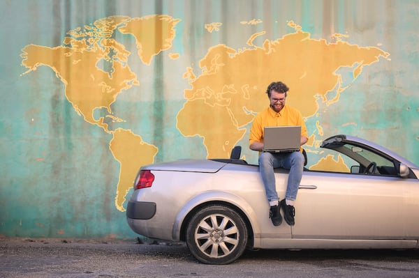 man sitting on car with laptop