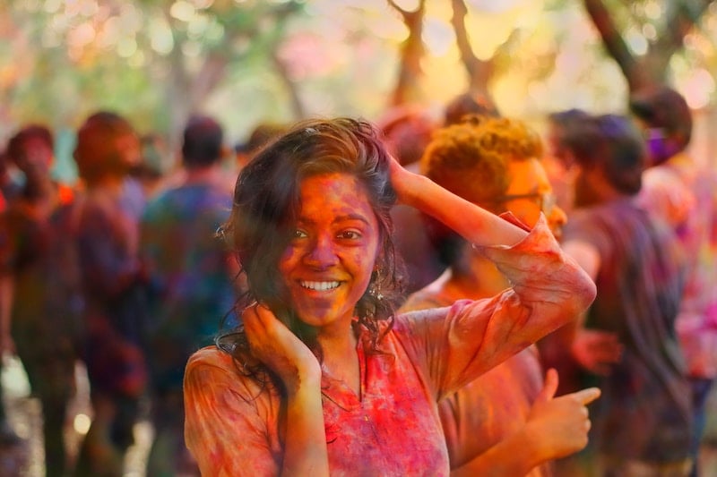A person covered in multi-coloured powder at an Indian festival.
