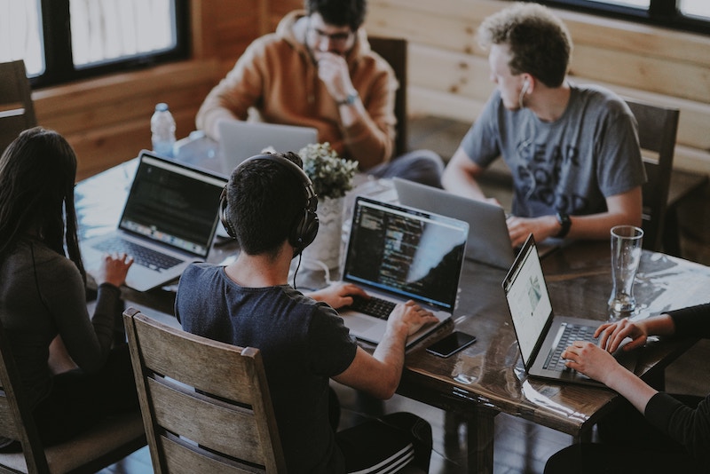 young people working at table with laptops