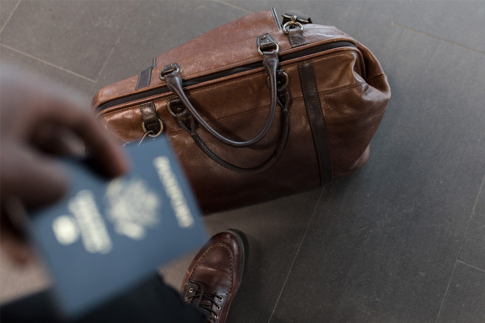 man standing over travel bag holding bank card