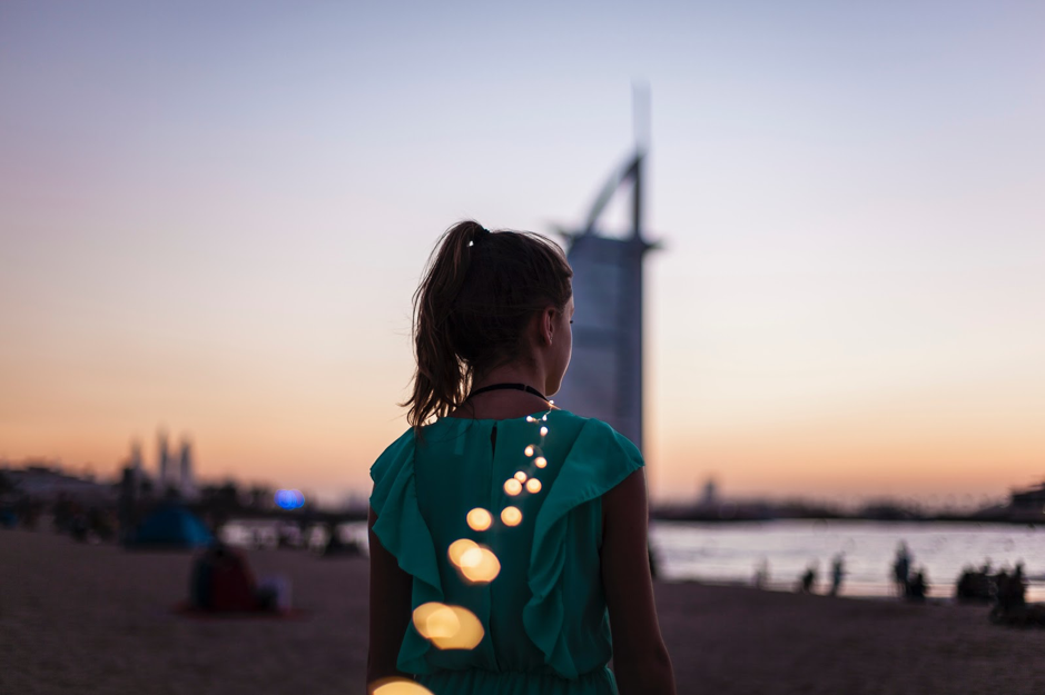 girl standing on beach near burj al arab