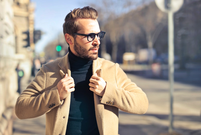 bearded man wearing glasses and coat in street