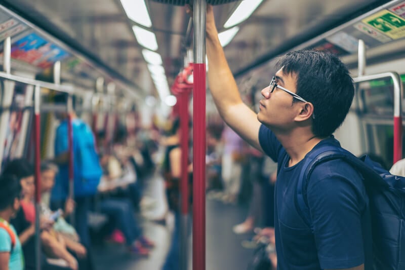 man looking up at roof of subway train