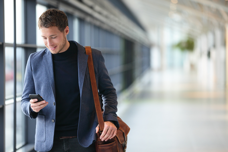 man on mobile phone in glass corridor smiling