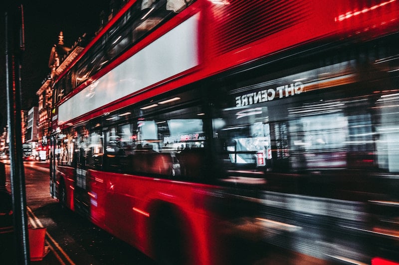 blurred shot of side of red london bus on street