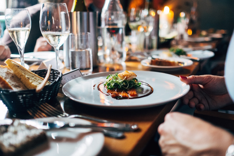 artistic dish of food on table in restaurant surrounded by glasses