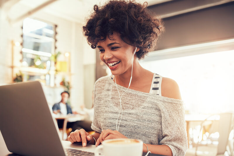 smiling woman working at laptop using headphones