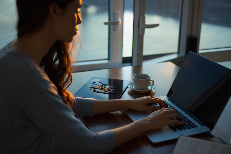 woman sitting at table with laptop and notebook