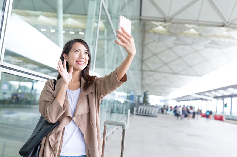 woman waving up on phone video call in airport