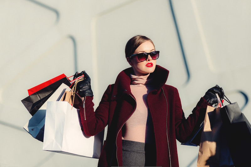 woman wearing sunglasses lifting shopping bags