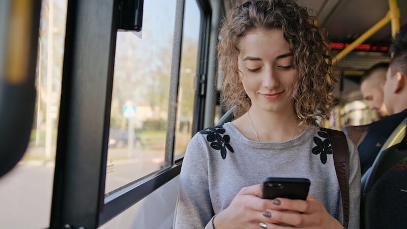 young woman on bus using mobile phone